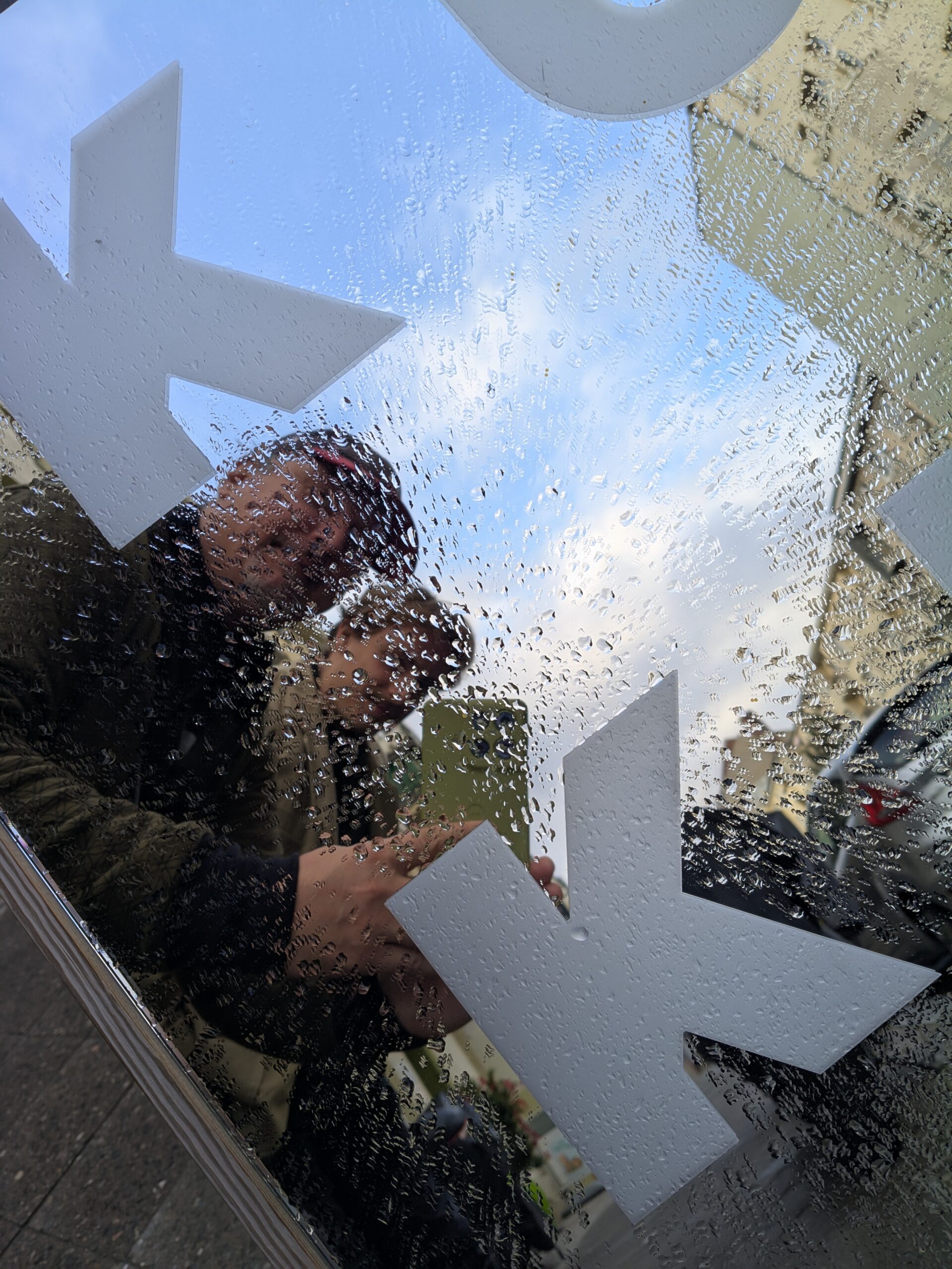 Ur.X logo behind rain-streaked glass, reflections before the record release show